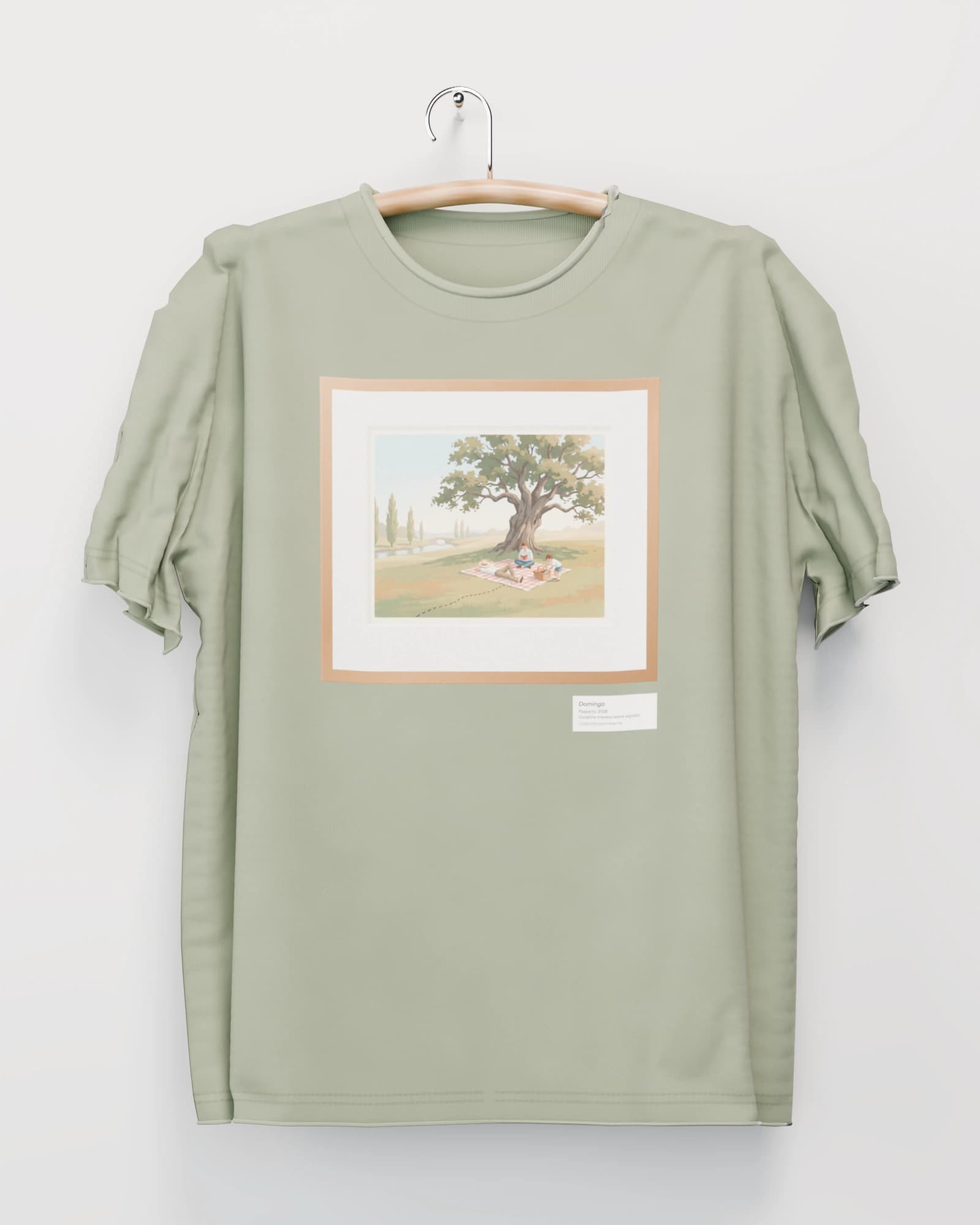Polera color salvia colgada de una percha de madera en un muro claro, con un picnic bajo un roble con una fila de hormigas, en marco de roble con paspartú en el pecho