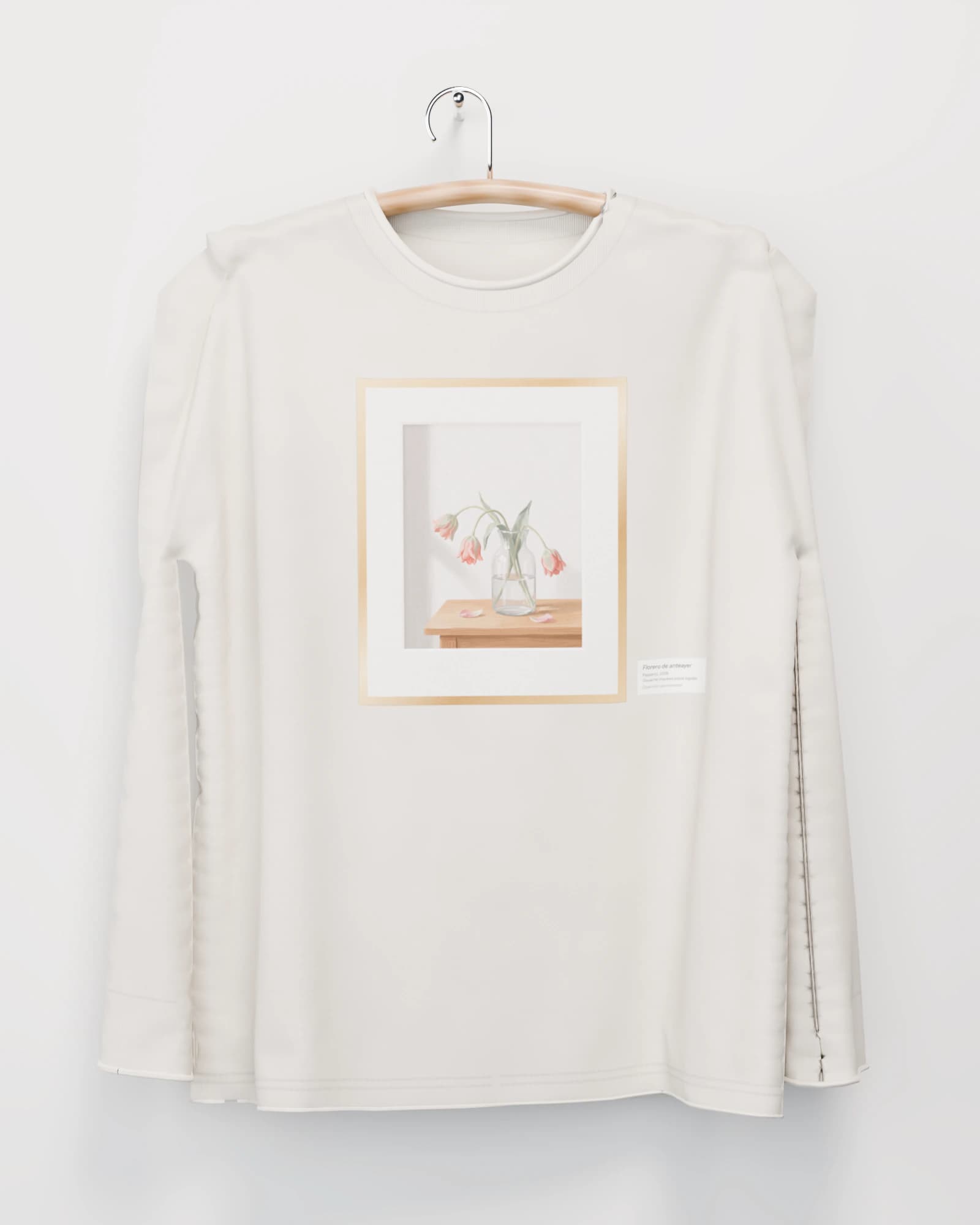 Polera manga larga color hueso colgada de una percha de madera en un muro claro, con tres tulipanes marchitos en un florero de vidrio, en marco dorado fino en el pecho