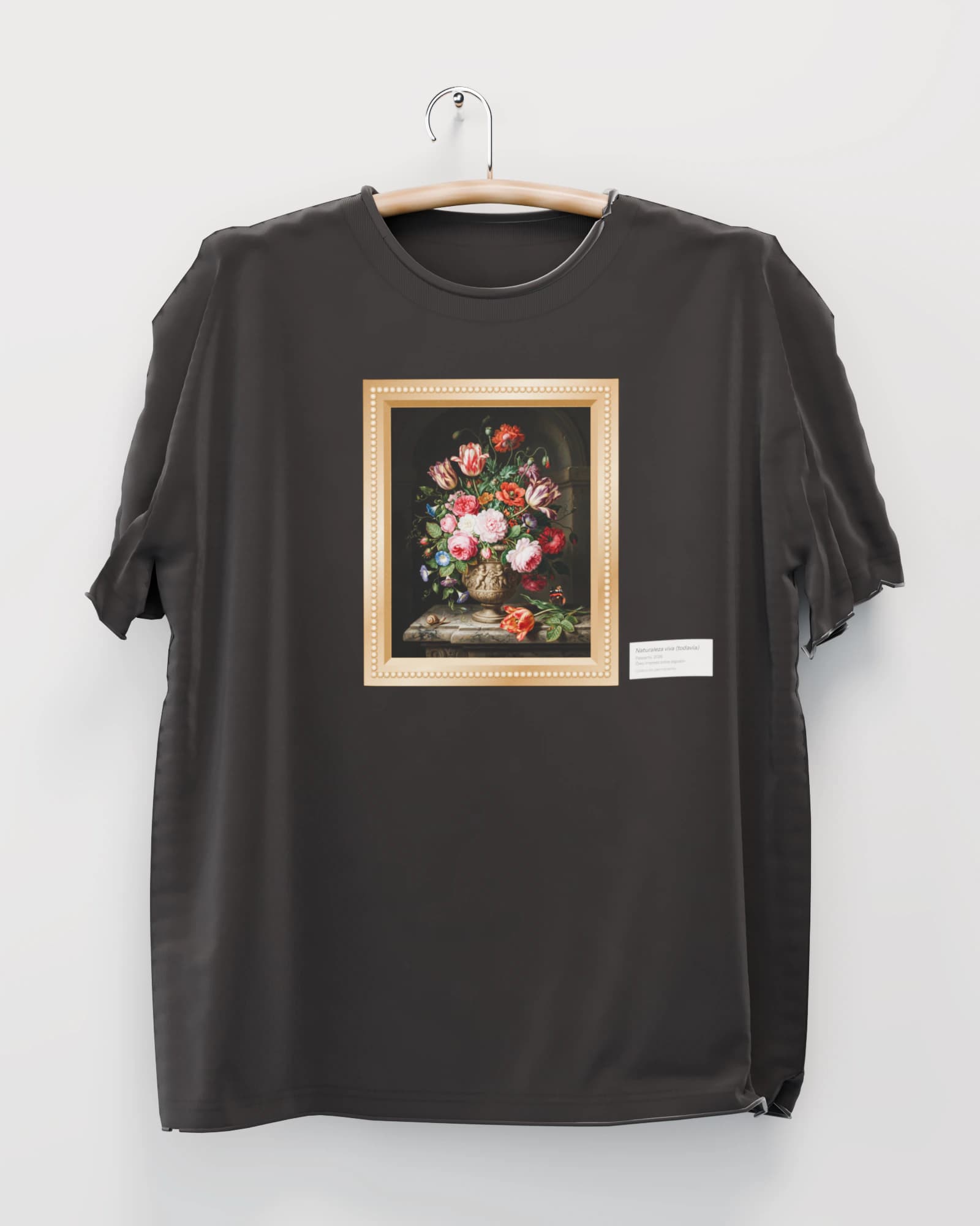 Polera color negro lavado colgada de una percha de madera en un muro claro, con un ramo de flores sobre fondo oscuro a la manera holandesa, en un marco dorado tallado en el pecho